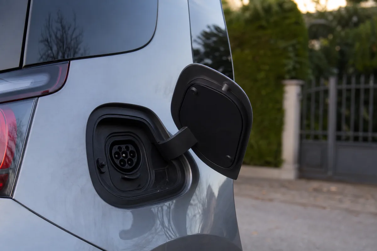 Prise de recharge ouverte sur le flanc d&rsquo;une voiture électrique compacte grise